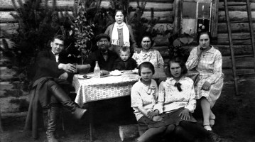 Семья Кямбре. Сидят за столом: Арнольд Оскарович, Оскар Петрович, Эльмар, Паулина, Людмила; сидят на брёвнышке: Альвина и Линда; стоит Элла